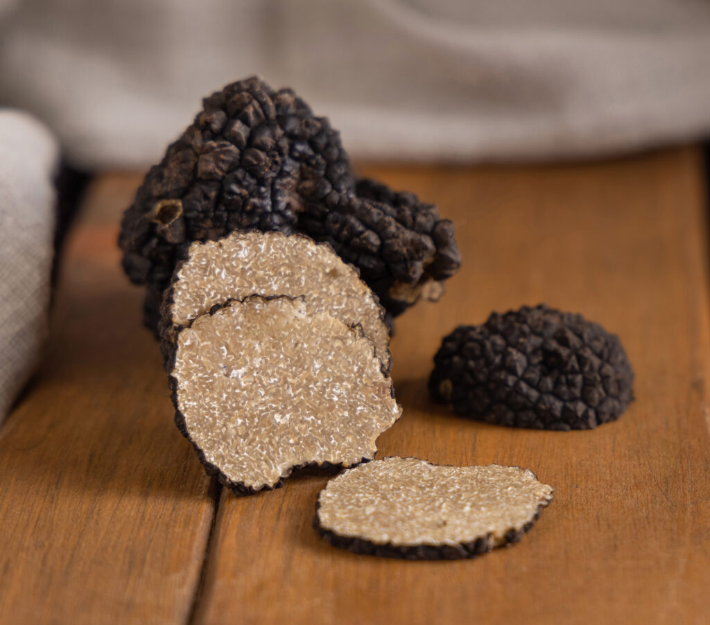 setas-de-trufas-negras-enteras-y-en-rodajas-sobre-tablero-de-madera-sobre-una-mesa-de-color-marron-oscuro-de-cerca